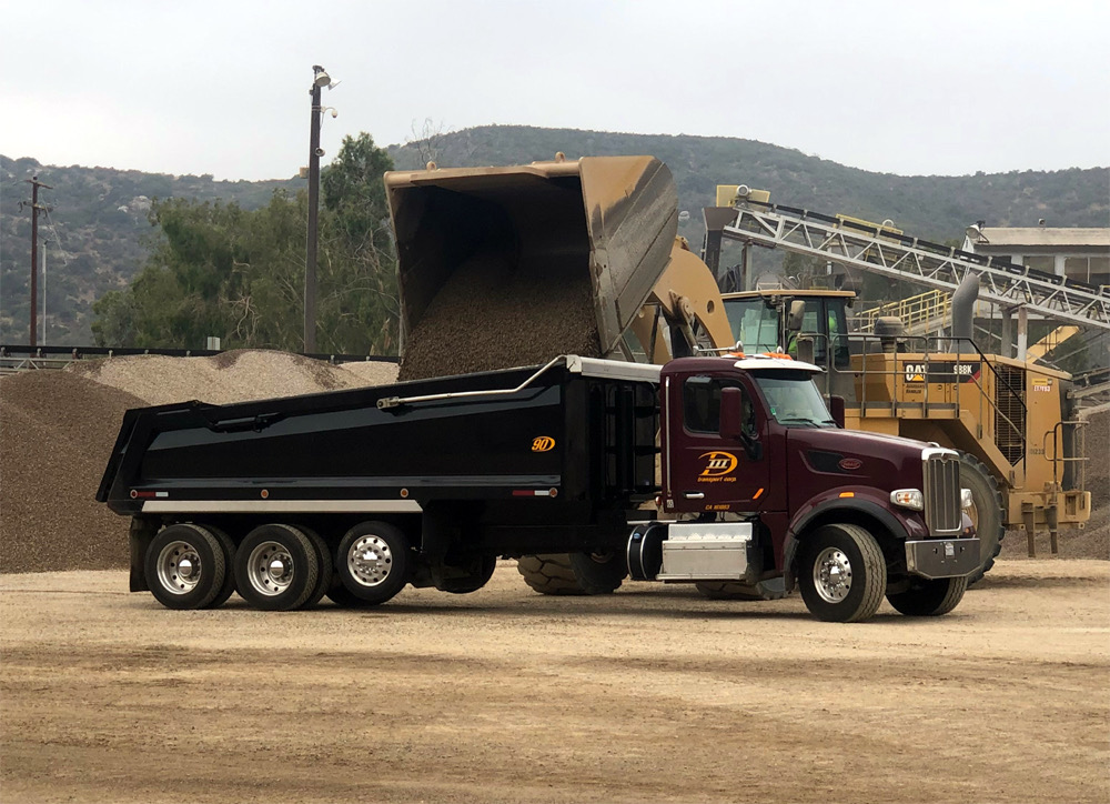 D III Transport truck being loaded with material at a jobsite