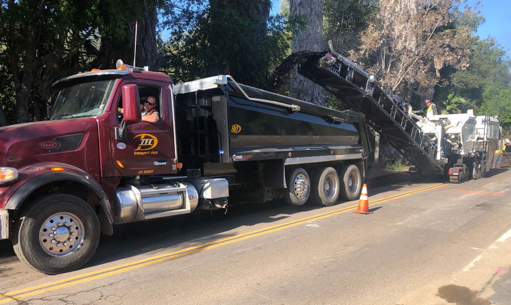 D III Transport truck alongside milling equipment on a paving job